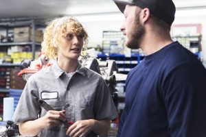 Two automotive mechanics having a discussion at their garage